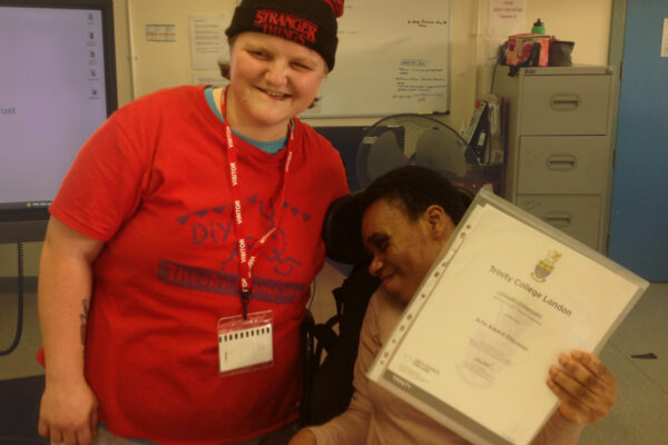 We can see DIY's Young Leader Charlotte posing with a young person who is holding up their Discover Arts Award Certificate.