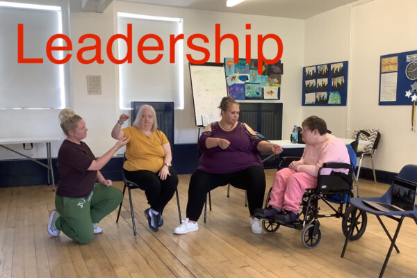 We can see a group of DIY members. Anna has her hand raised and looks like she is about to drop something into Molly's hand. Becky is talking to Cathy who is listening well.