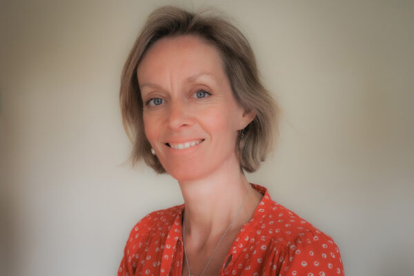photo of Clare, DIY's Access Coordinator. Clare is blond with blue eyes and in this picture she is smiling and wearing a red blouse.